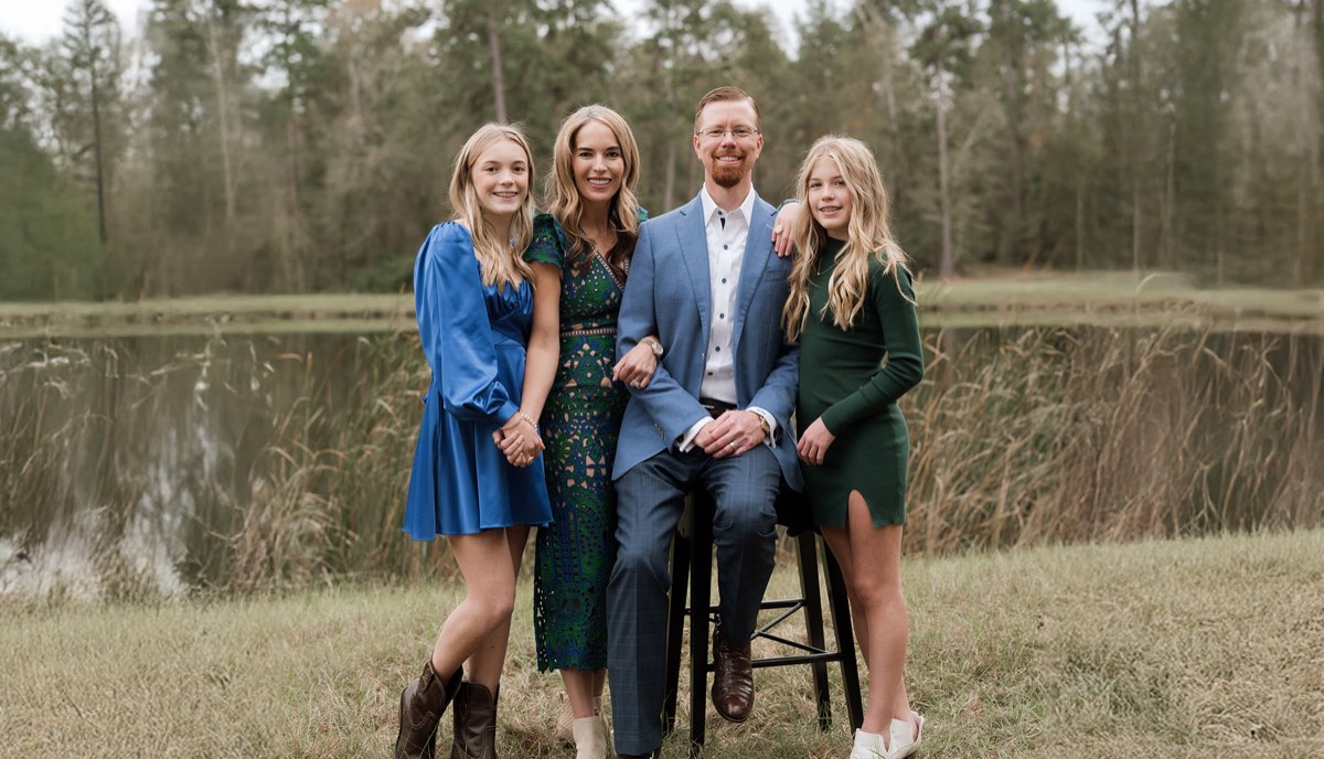 State Representative Will Metcalf with his family outdoors beside a pond.
